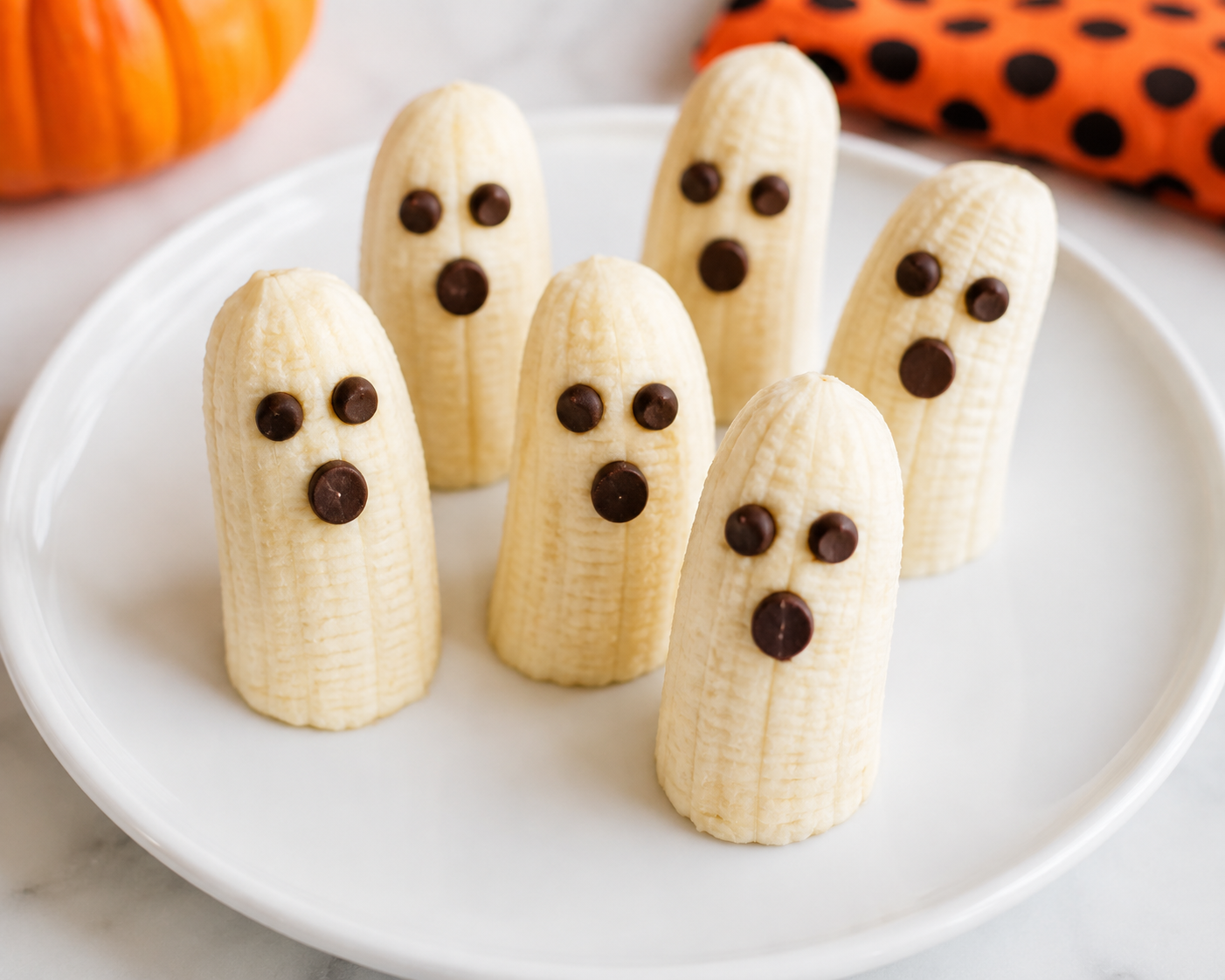 Banana ghost snacks decorated with chocolate chip eyes and mouths.