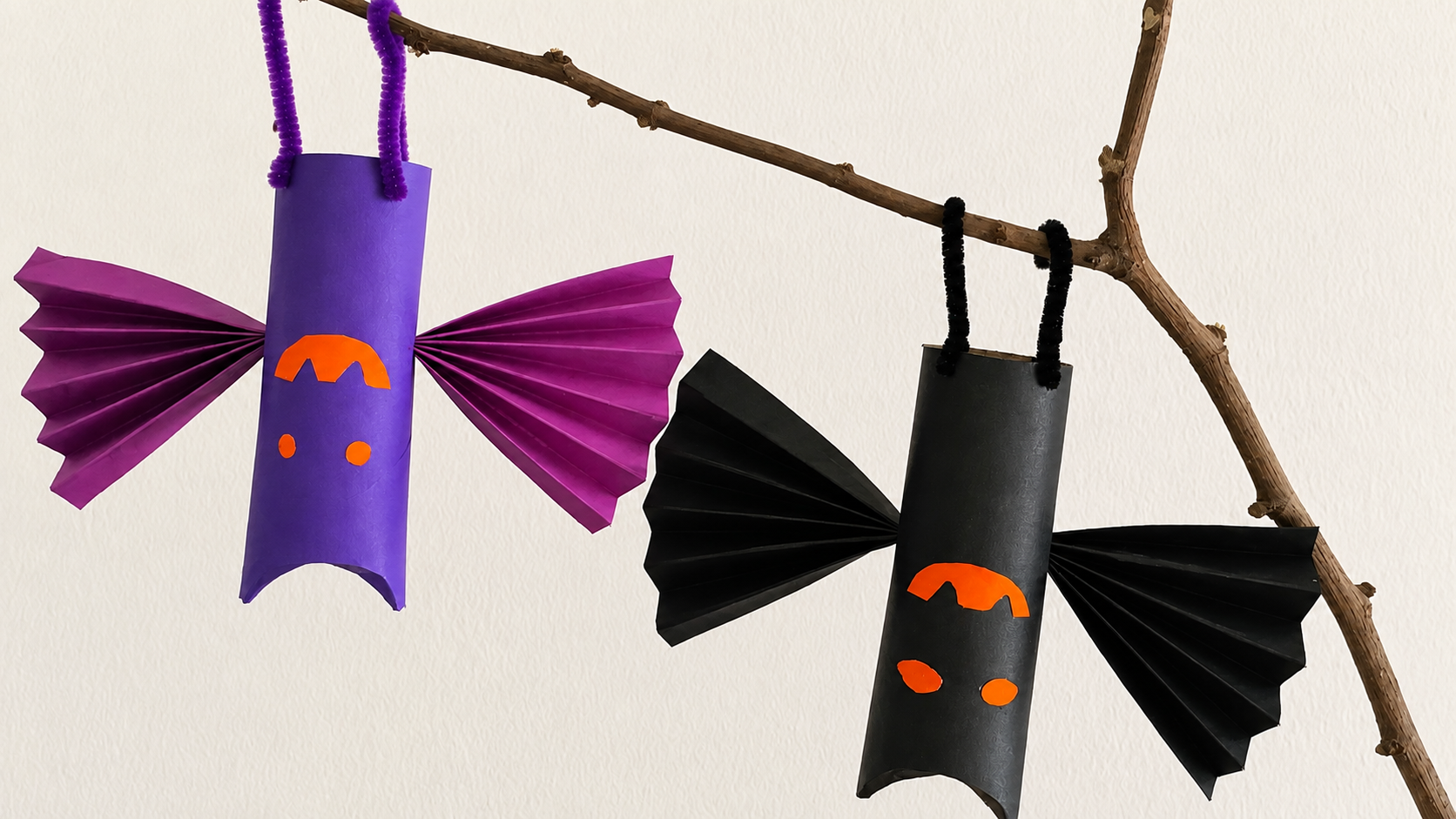 Purple and black hanging bat crafts made from paper rolls with folded paper wings.