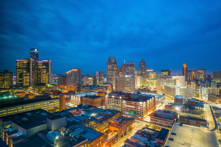 Nighttime cityscape: downtown skyline lit by building and street lights, seen from an elevated view under a blue evening sky.
