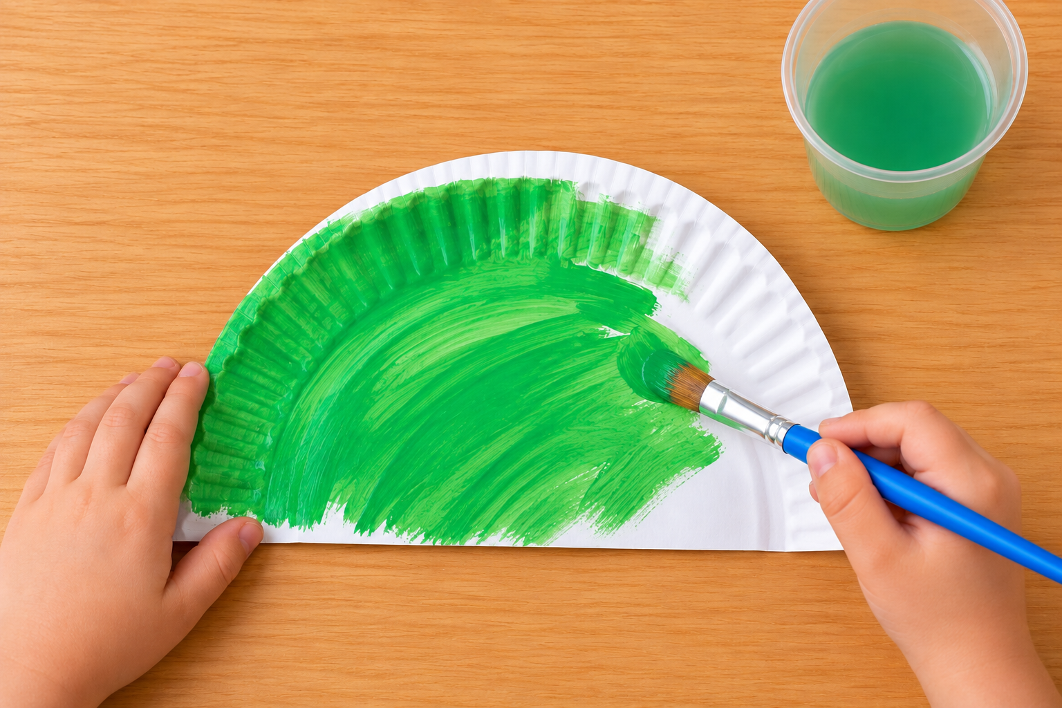 Green painted paper plate dinosaur body and painted cardboard tube legs drying on a wooden table.