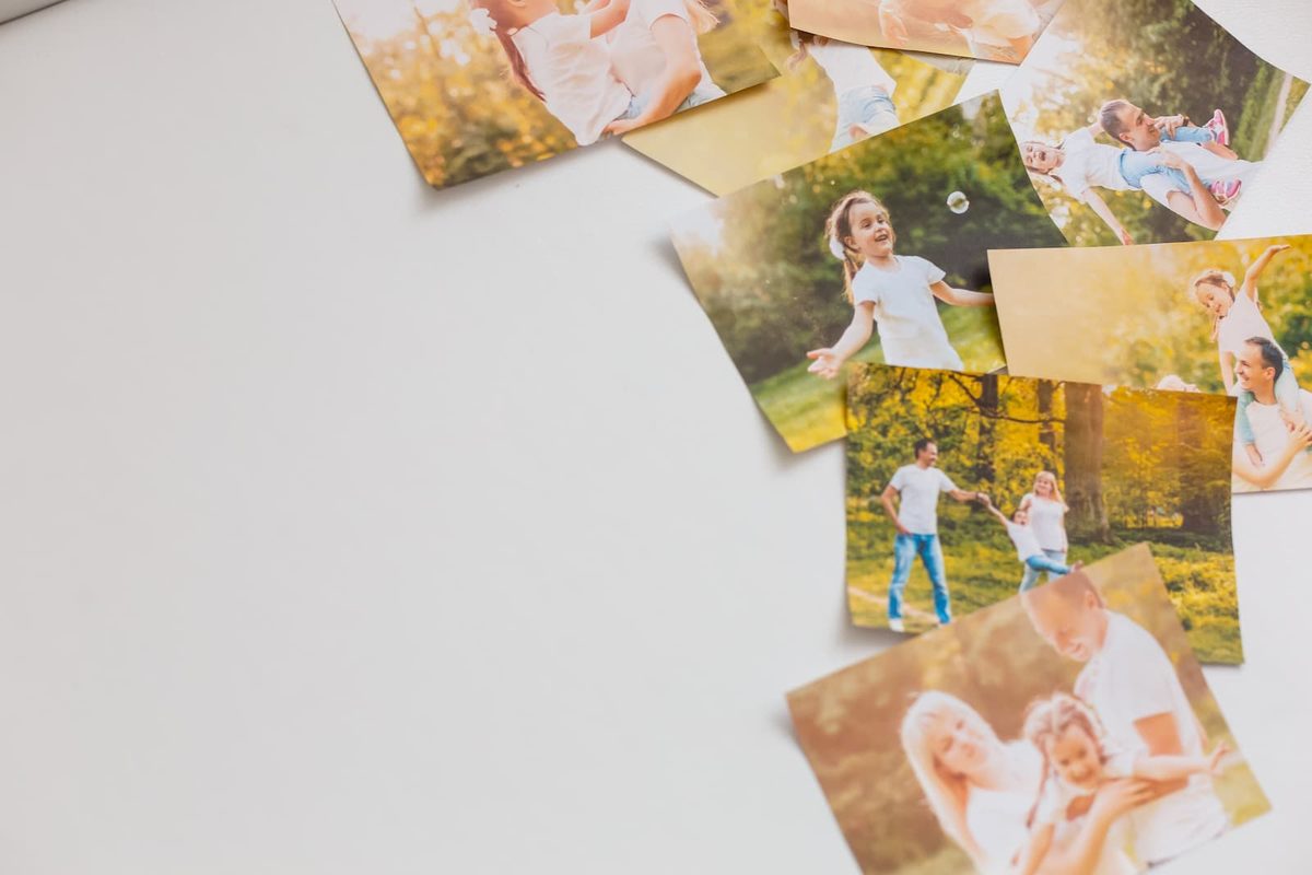 Printed family photos featuring favorite people and memories arranged around a blank poster board for a children's gratitude activity.